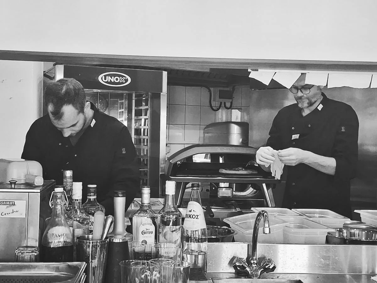 Both Pizza Pirates crew members preparing pizzas beside their portable oven