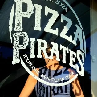 Pizza Pirates logo on glass with a person behind it