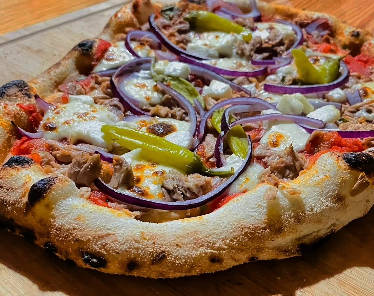 Fresh pizza with red onion rings and green peppers