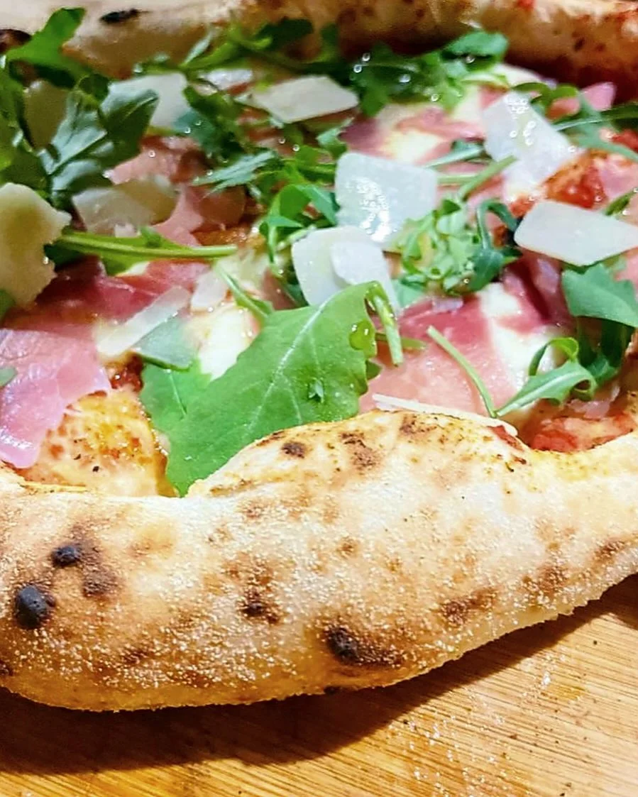 Pizza with an airy crust, rocket, cured meat and shaved cheese
